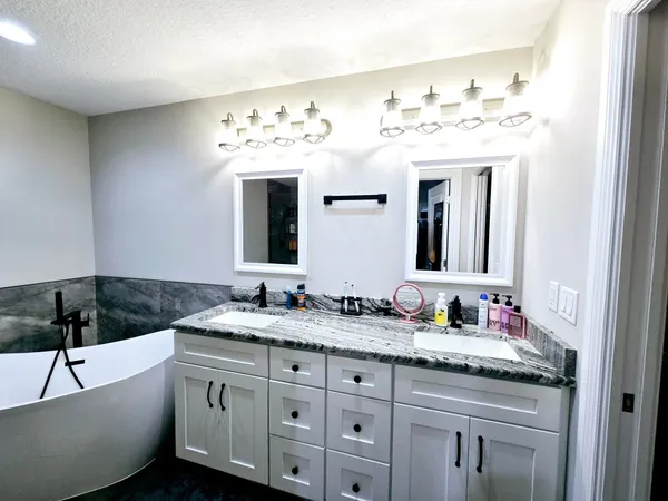 a bathroom with a granite countertop sink mirror and bathtub