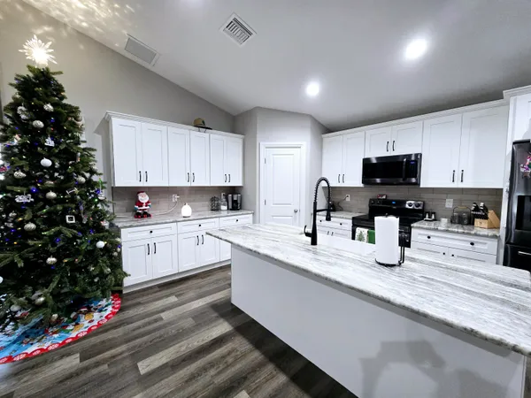 a kitchen with granite countertop a sink dishwasher a microwave oven and a refrigerator with wooden cabinets