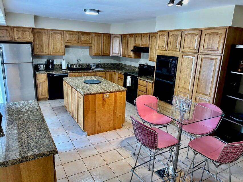 1420 Ocean Way, Unit 14D Jupiter, FL 33477 - Photo 3 of 34 a kitchen with stainless steel appliances kitchen island granite countertop a refrigerator a sink dishwasher a dining table and chairs with wooden floor