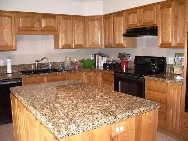 a kitchen with granite countertop a sink a stove and a wooden cabinets