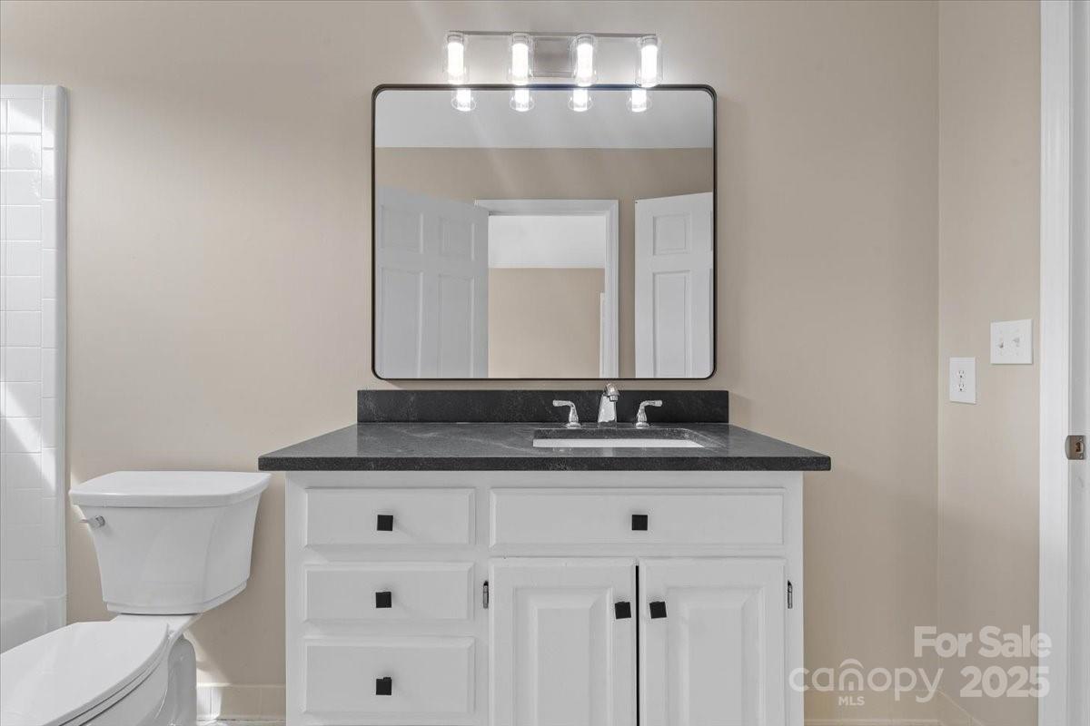 5916 Cashion Road Huntersville, NC 28078 - Photo 28 of 45 a bathroom with a granite countertop sink a toilet and a mirror