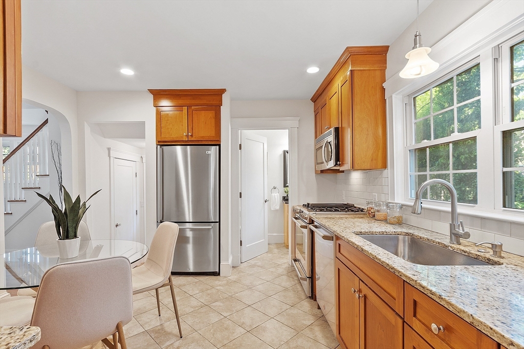 15 Marion Road Watertown, MA 02472 - Photo 12 of 41 a kitchen with stainless steel appliances granite countertop a refrigerator a sink a stove and white cabinets with wooden floor