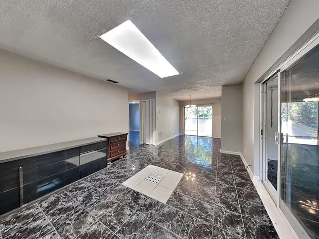 a view of a hallway to an empty room and window