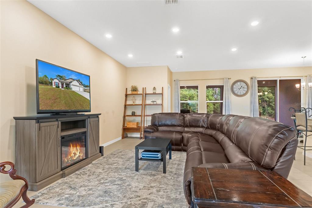 6283 Grapewood Road Spring Hill, FL 34609 - Photo 12 of 41 a living room with furniture a fireplace and a flat screen tv