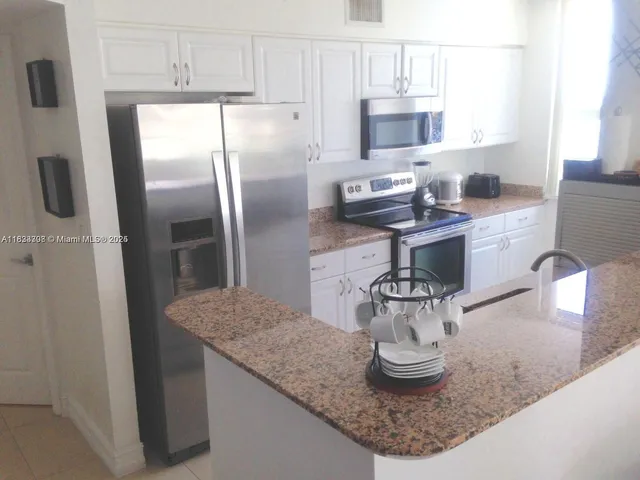 a kitchen with stainless steel appliances granite countertop a sink and a refrigerator