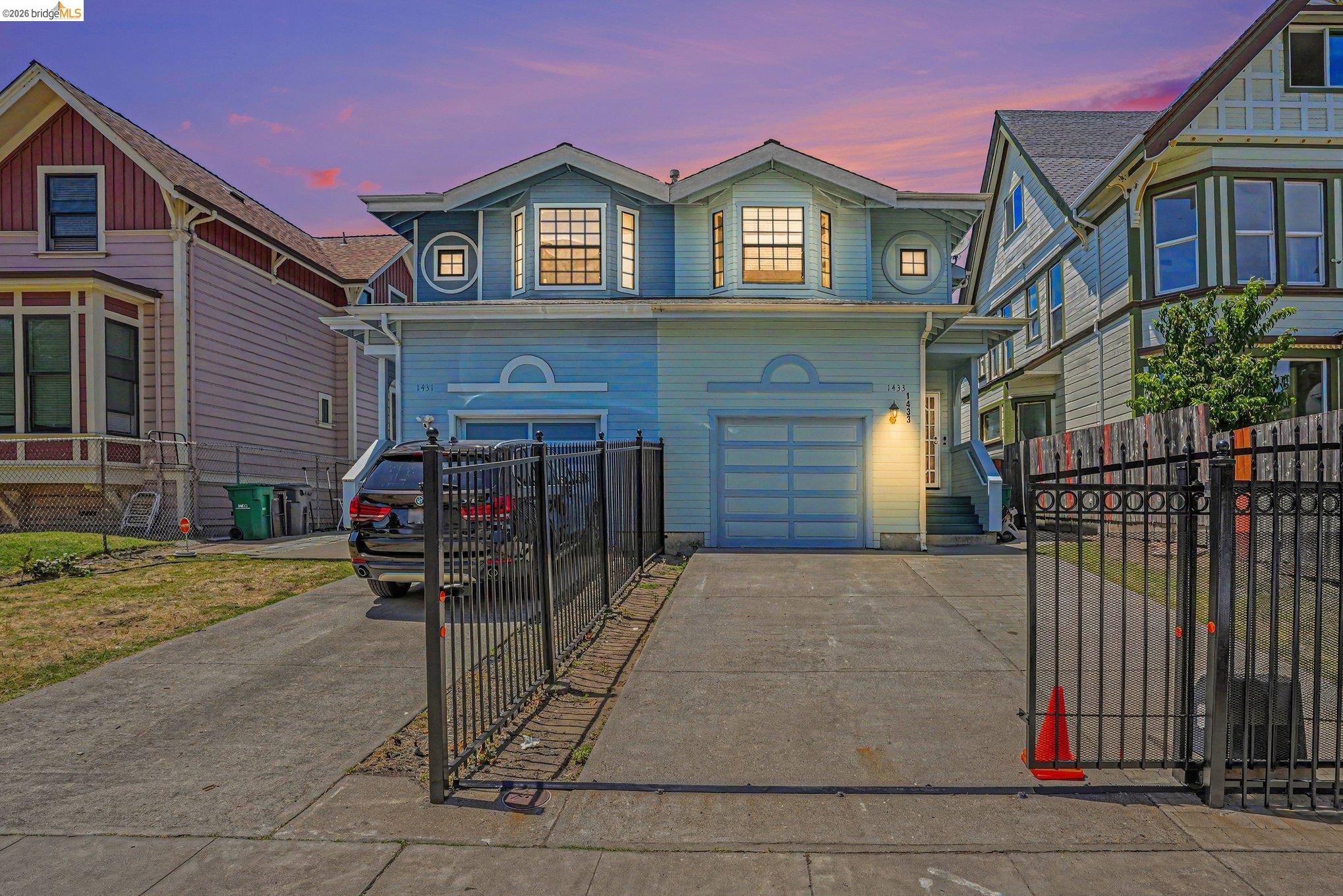 1433 Myrtle Street Oakland, CA 94607 - Photo 23 of 25 Light blue stucco exterior featuring a two-car garage with horizontal paneling, two prominent bay windows, and a concrete driveway