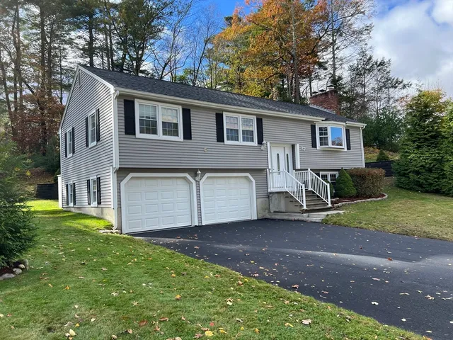 a view of a house with a yard and large tree