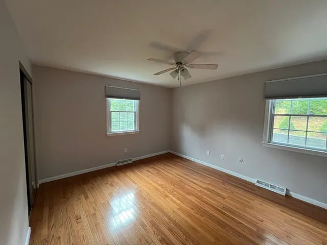 an empty room with wooden floor and windows
