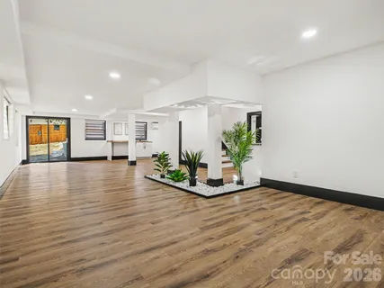 a view of an empty room with wooden floor and a potted plant