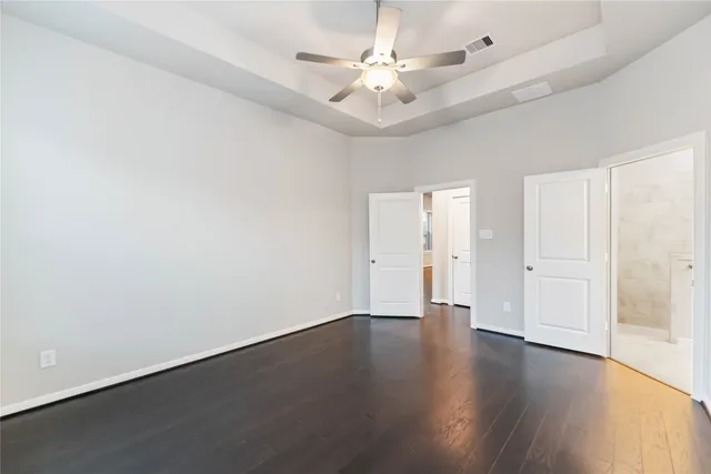 an empty room with wooden floor and ceiling fan