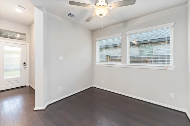an empty room with wooden floor and windows