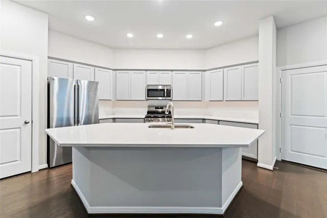 a view of kitchen with stainless steel appliances wooden floor and window