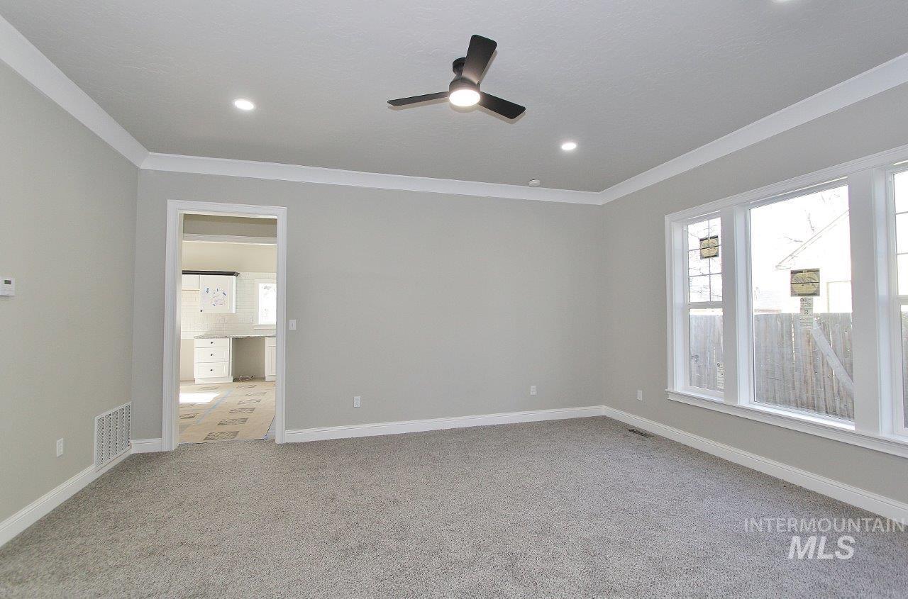 121 Northwest 2nd Street Ontario, OR 97914 - Photo 14 of 32 Empty room with a ceiling fan, light carpet, and ornamental molding