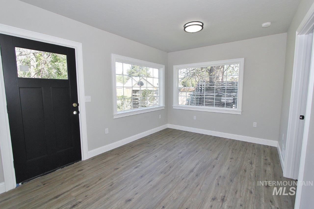 121 Northwest 2nd Street Ontario, OR 97914 - Photo 16 of 32 Entryway featuring a black door with upper glass pane, wood-finish flooring, light gray walls, white trim, and two large windows