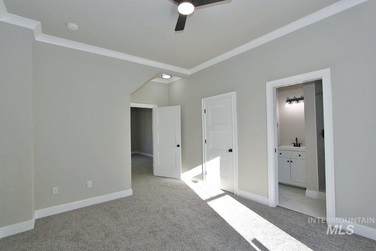 121 Northwest 2nd Street Ontario, OR 97914 - Photo 17 of 32 Unfurnished bedroom featuring ornamental molding, light carpet, ensuite bathroom, and a ceiling fan