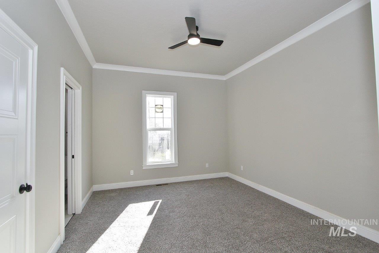 121 Northwest 2nd Street Ontario, OR 97914 - Photo 18 of 32 Unfurnished bedroom featuring crown molding, light carpet, and a ceiling fan