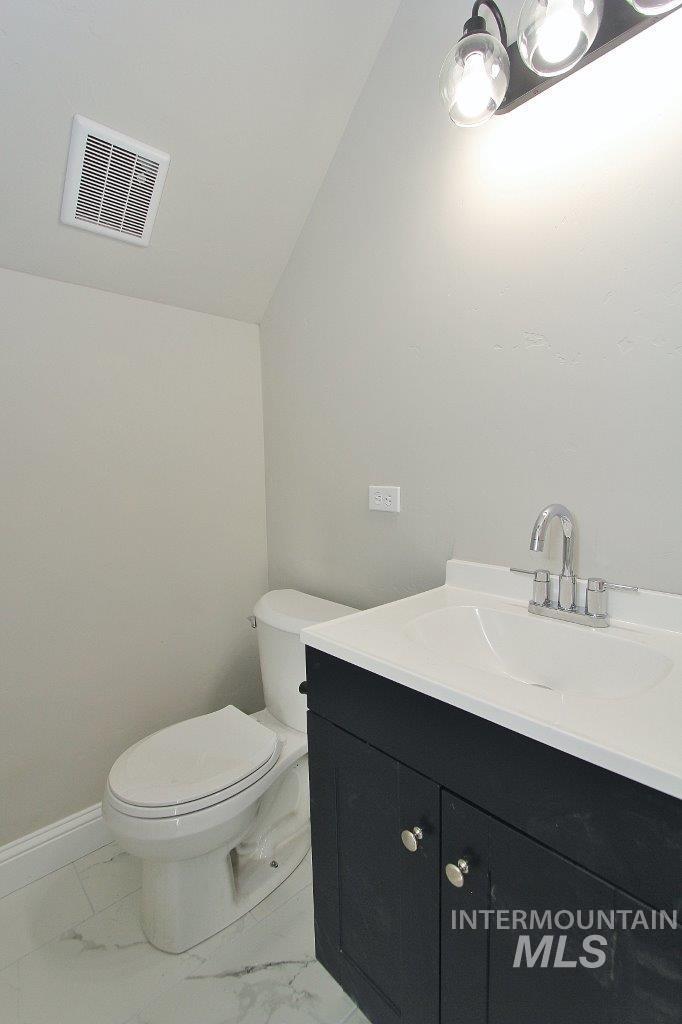 121 Northwest 2nd Street Ontario, OR 97914 - Photo 26 of 32 Half bath featuring vanity, vaulted ceiling, and light marble finish floors