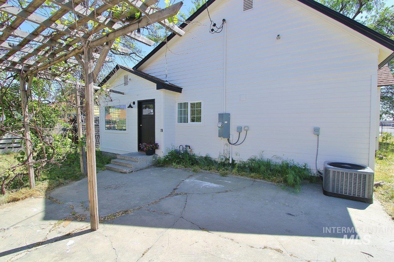 121 Northwest 2nd Street Ontario, OR 97914 - Photo 3 of 32 White siding exterior featuring a dark entry door, multiple windows, and a wood pergola structure
