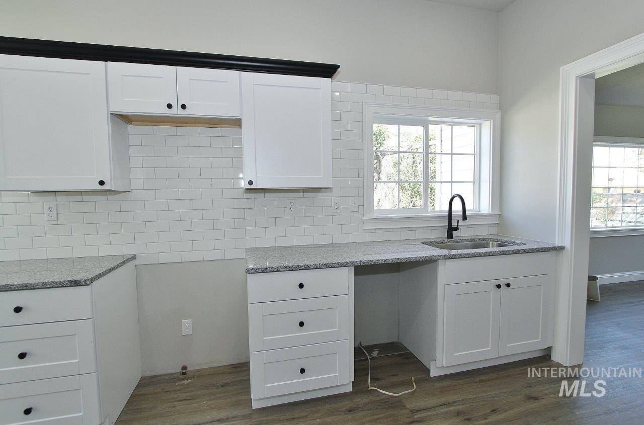 121 Northwest 2nd Street Ontario, OR 97914 - Photo 6 of 32 Kitchen featuring white shaker cabinetry, white subway tile backsplash, granite-style countertops, and wood-finish flooring