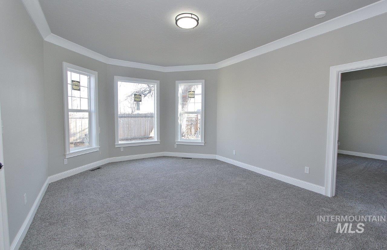 121 Northwest 2nd Street Ontario, OR 97914 - Photo 9 of 32 Carpeted spare room with plenty of natural light and crown molding
