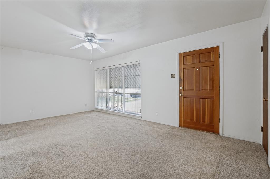 2528 Rugby Lane Farmers Branch, TX 75234 - Photo 2 of 12 Carpeted interior with a paneled wood entry door, white ceiling fan, and large window with blinds