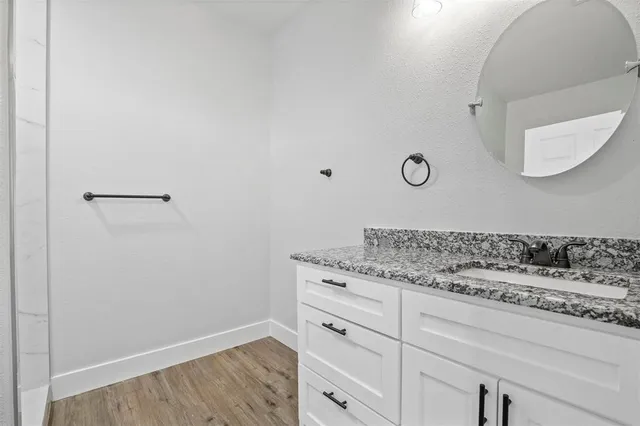 a bathroom with a granite countertop sink and white cabinets