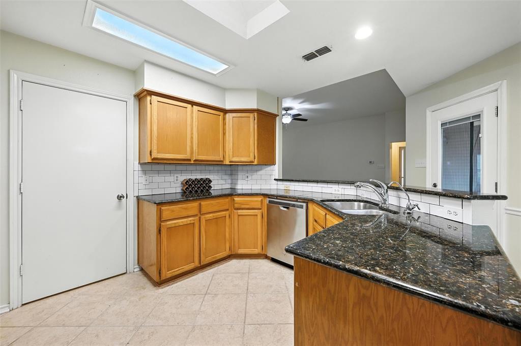 Kitchen with decorative backsplash, a peninsula, dark stone counters, and dishwasher