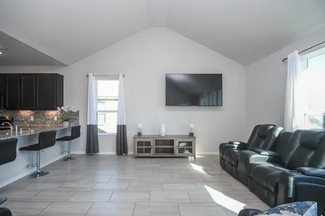 a living room with furniture a ceiling fan and a flat screen tv