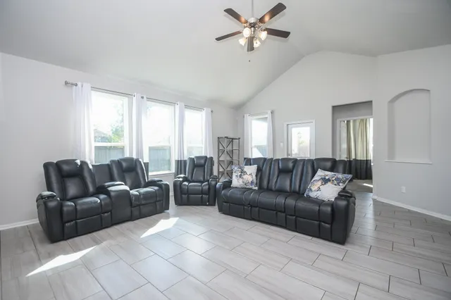 a living room with furniture a ceiling fan a fireplace and a window