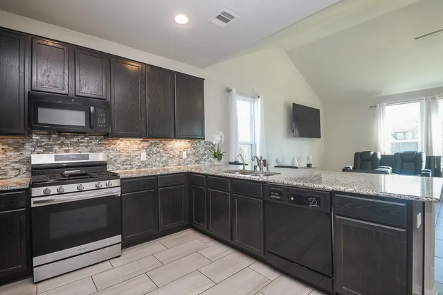 a kitchen with kitchen island granite countertop wooden cabinets and a refrigerator