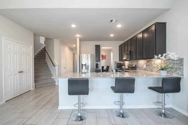 a kitchen with granite countertop a refrigerator a stove a sink and a cabinets