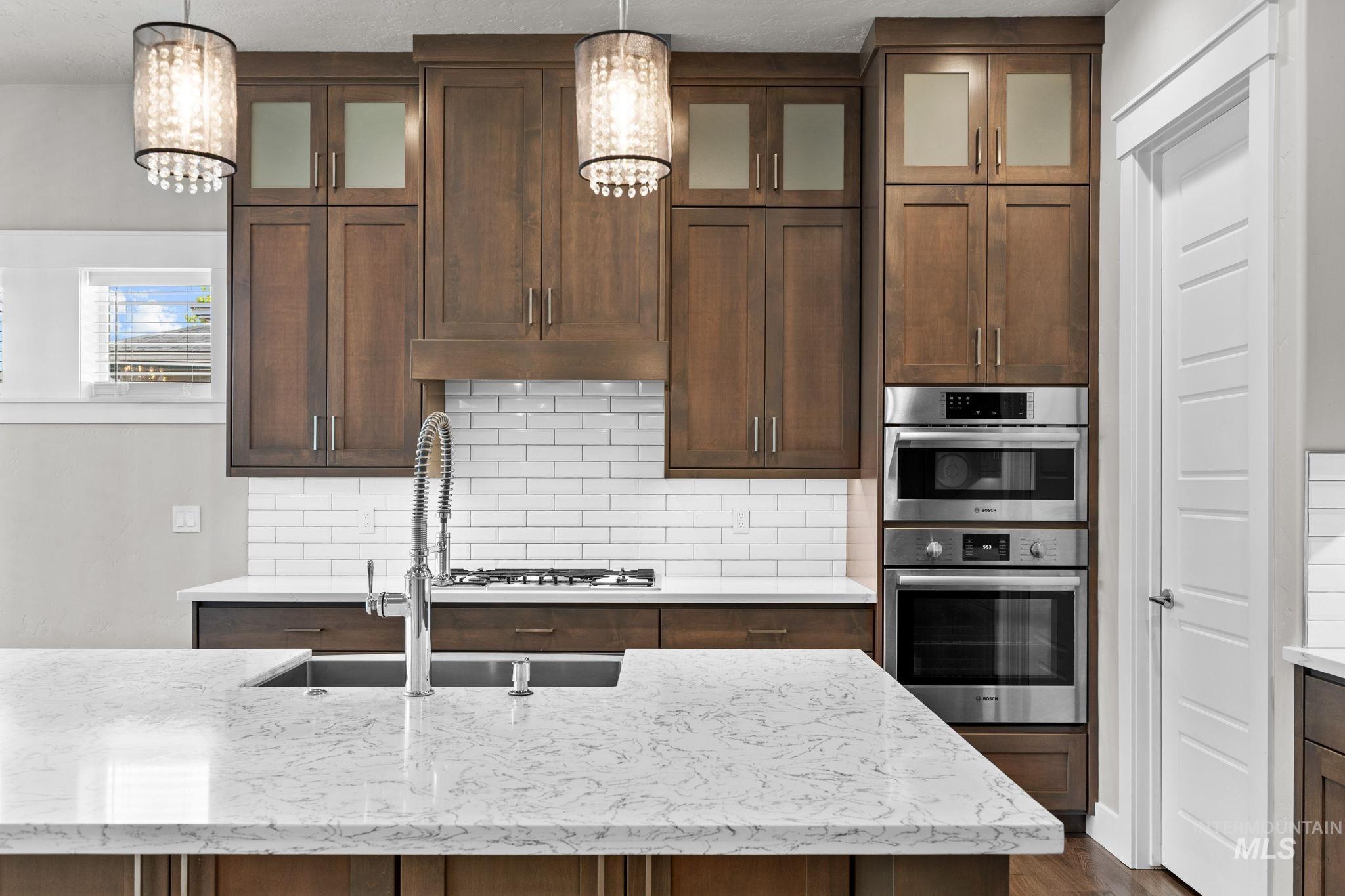 2934 East Murchison Street Meridian, ID 83642 - Photo 10 of 44 Gourmet kitchen featuring a large island with white stone countertops, dark wood cabinetry, stainless steel appliances, and subway tile backsplash