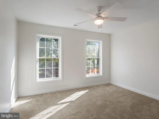 an empty room with chandelier fan and windows