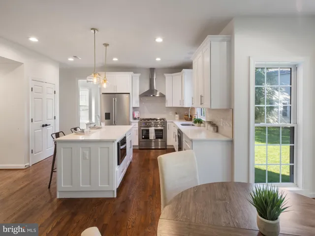 a kitchen with kitchen island granite countertop a stove a sink a refrigerator and white cabinets with wooden floor