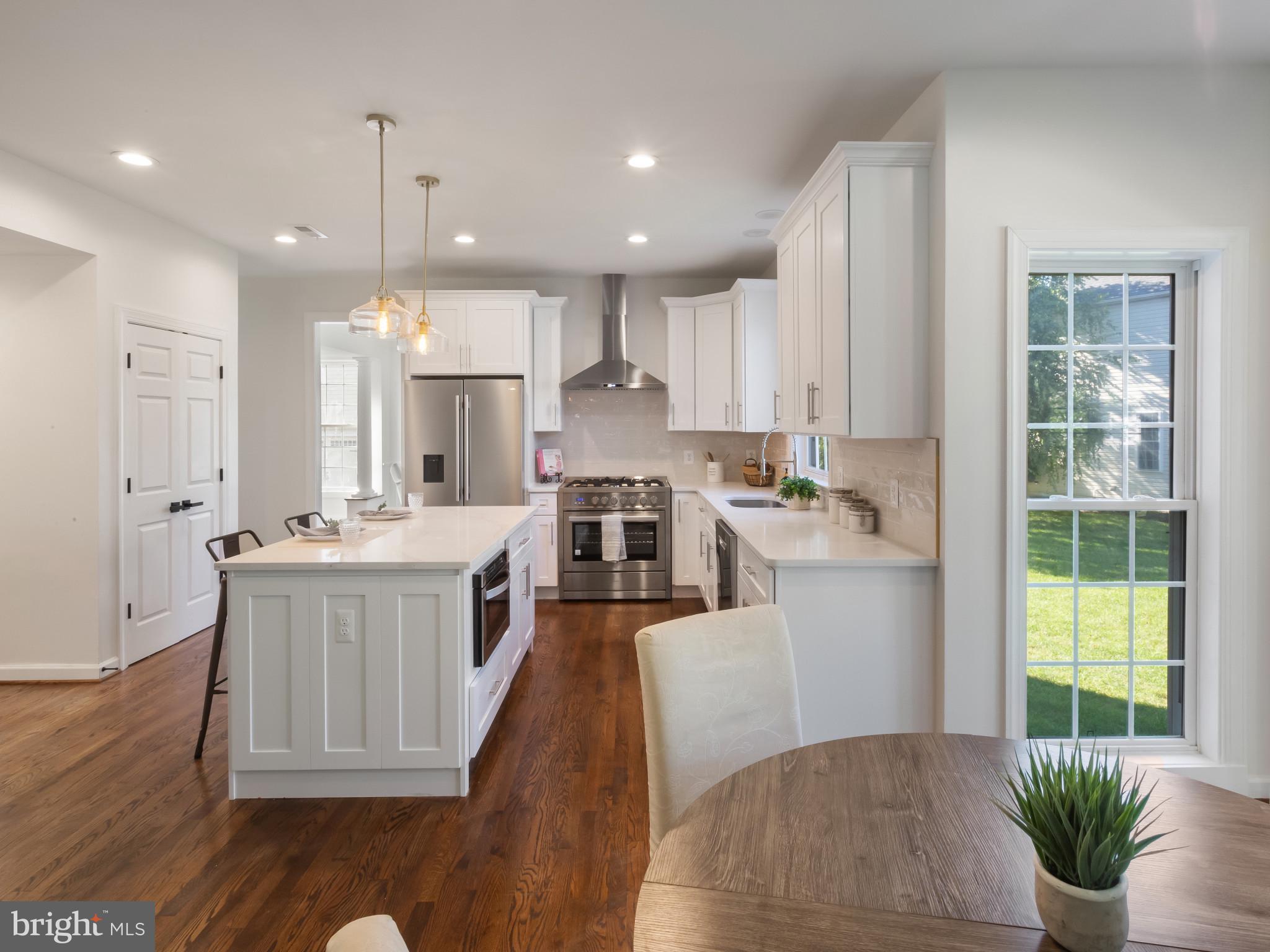 1612 Winesapp Drive Odenton, MD 21113 - Photo 4 of 34 a kitchen with kitchen island granite countertop a stove a sink a refrigerator and white cabinets with wooden floor