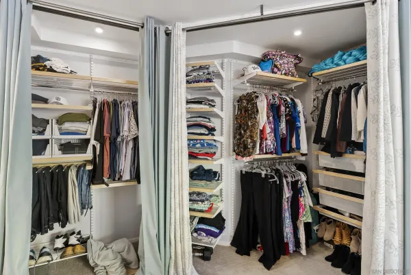a view of walk in closet with clothes and shoes