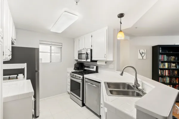 a kitchen with white cabinets a sink and appliances