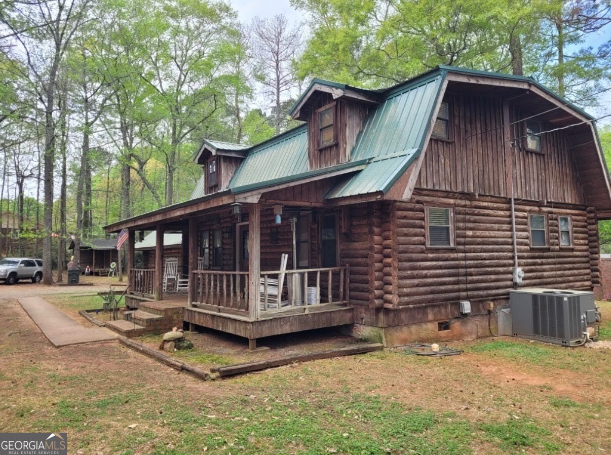 a view of wooden house with a yard large tree and a wooden fence