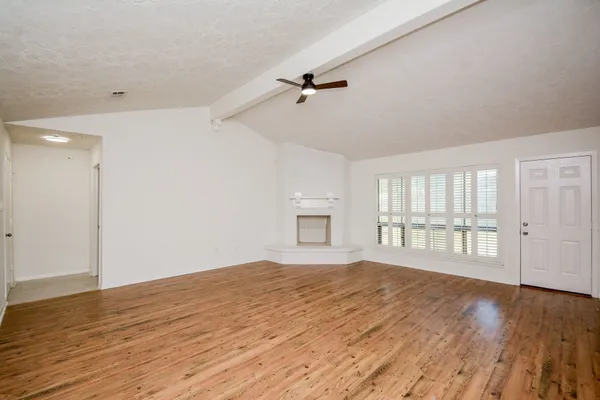 a view of an empty room with wooden floor and a window
