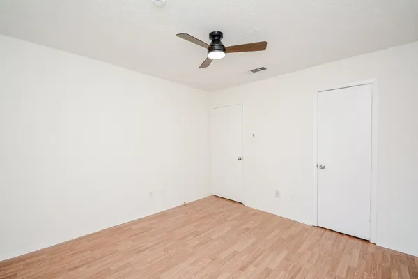 a view of a room with wooden floor and a ceiling fan