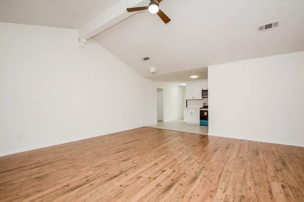 a view of empty room with wooden floor and fan