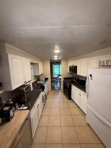 a large white kitchen with cabinets a sink a stove and a refrigerator