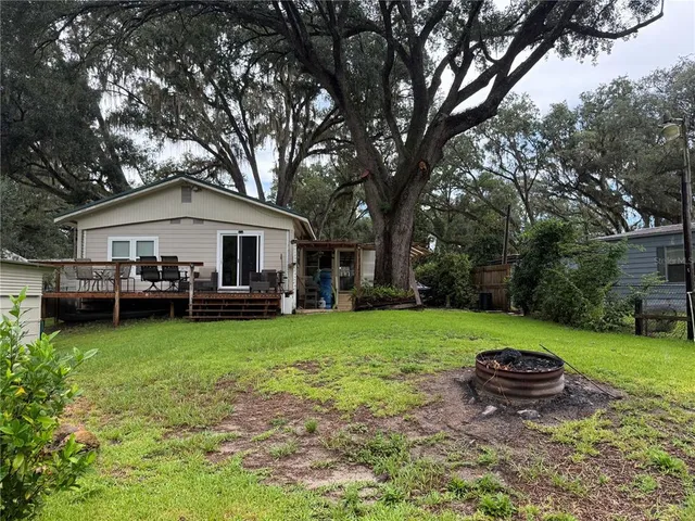 a view of a yard in front of a house with large trees and plants
