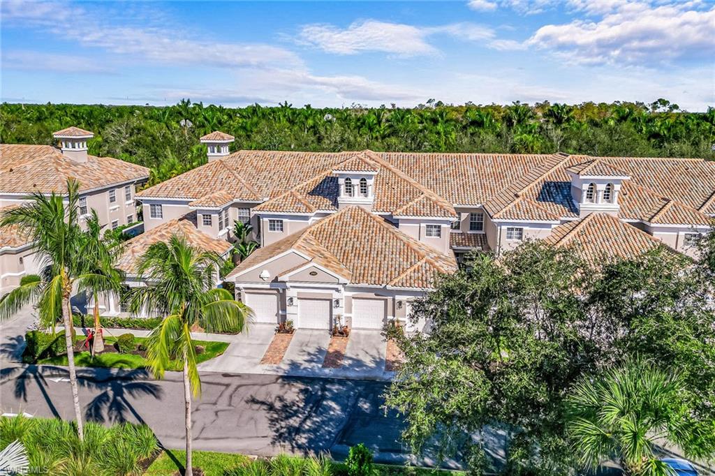 3985 Deer Crossing Court, Unit 103 Naples, FL 34114 - Photo 1 of 37 an aerial view of multiple houses with a yard