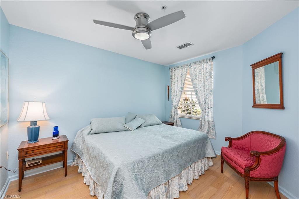 3985 Deer Crossing Court, Unit 103 Naples, FL 34114 - Photo 11 of 37 a bedroom with a bed and a chandelier