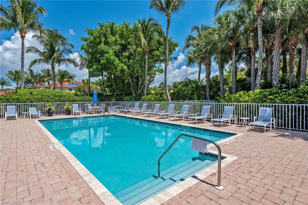 3985 Deer Crossing Court, Unit 103 Naples, FL 34114 - Photo 26 of 37 a view of a swimming pool with a lounge chair and palm trees