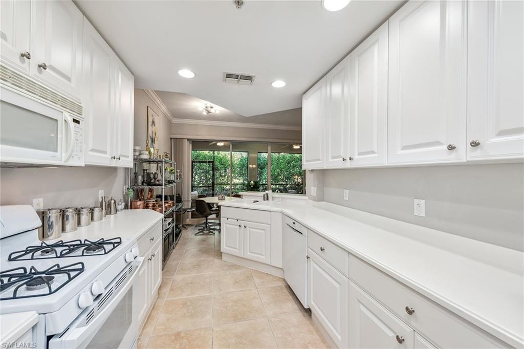 3985 Deer Crossing Court, Unit 103 Naples, FL 34114 - Photo 5 of 37 a large white kitchen with stainless steel appliances granite countertop a stove a sink a refrigerator and white cabinets