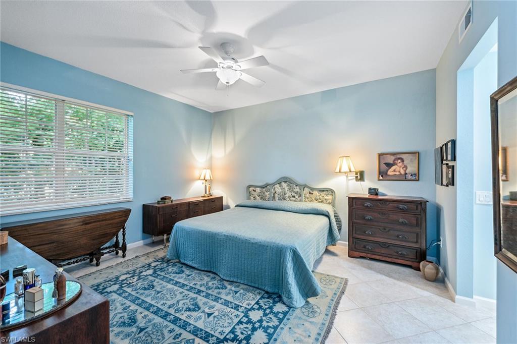 3985 Deer Crossing Court, Unit 103 Naples, FL 34114 - Photo 8 of 37 a bedroom with a bed and a chandelier