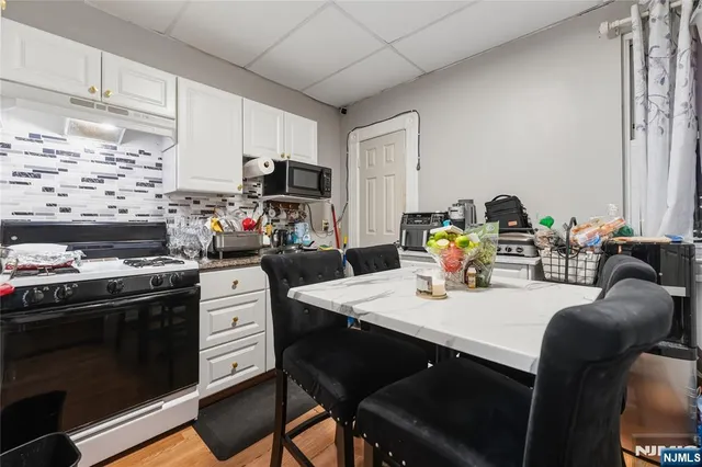 a kitchen with stainless steel appliances a stove a sink a dining table and chairs