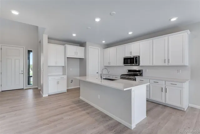 a kitchen with stainless steel appliances granite countertop a stove top oven a sink and white cabinets